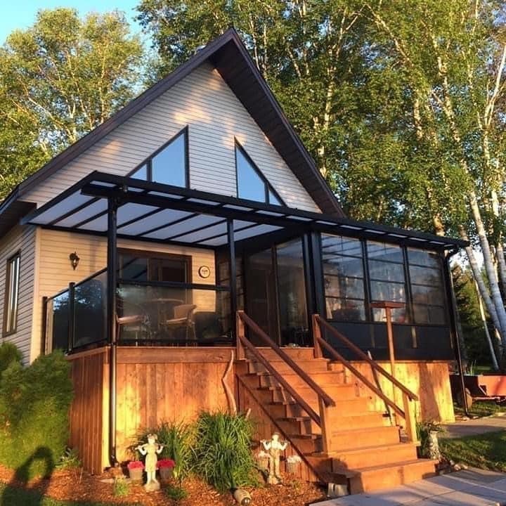Véranda aménagée avec foyer, mobilier confortable et vue sur un jardin, exemple de cour équipée pour y vivre.